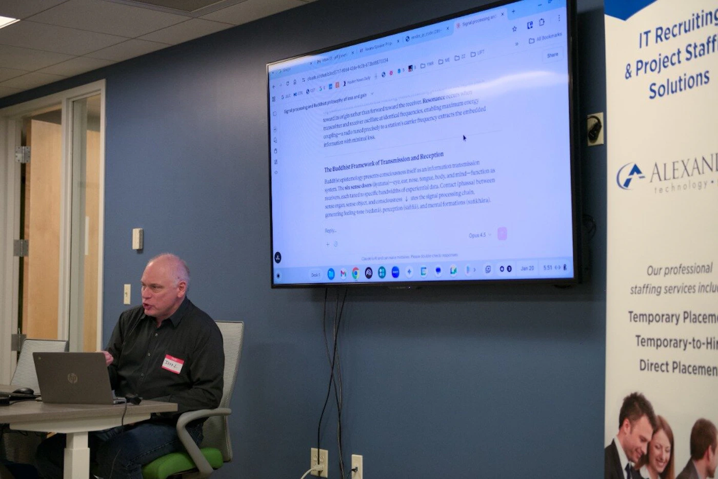 (Photo) A man is sitting at a desk with a laptop, giving a presentation in an office. A large screen behind him displays text about a Buddhist framework of transmission and reception. Text: IT Recruiting & Project Staffing Solutions ALEXANDRIA technology Our professional staffing services include: Temporary Placement Temporary-to-Hire Direct Placement The Buddhist Framework of Transmission and Reception Buddhist epistemology presents consciousness itself as an information transmission system. The six sense doors (ayatana)—eye, ear, nose, tongue, body, and mind—function as receivers, each tuned to specific bandwidths of experiential data. Contact (phassa) between sense organ, sense object, and consciousness triggers the signal processing chain, generating feeling tone (vedana), perception (saññā), and mental formations (sankhāra). Resonance occurs when transmitter and receiver oscillate at identical frequencies, enabling maximum energy coupling—a radio tuned precisely to a station's carrier frequency extracts the embedded information with minimal loss. Opus 4.5 Jerry L. hp person, presentation, office | indoor | large monitor with text, recruitment banner, laptop, name tag | candid | Colors: #2b3d51, #ffffff, #000000 Note: The image is a photograph capturing a real-life scene of a person in a professional office environment during a presentation.