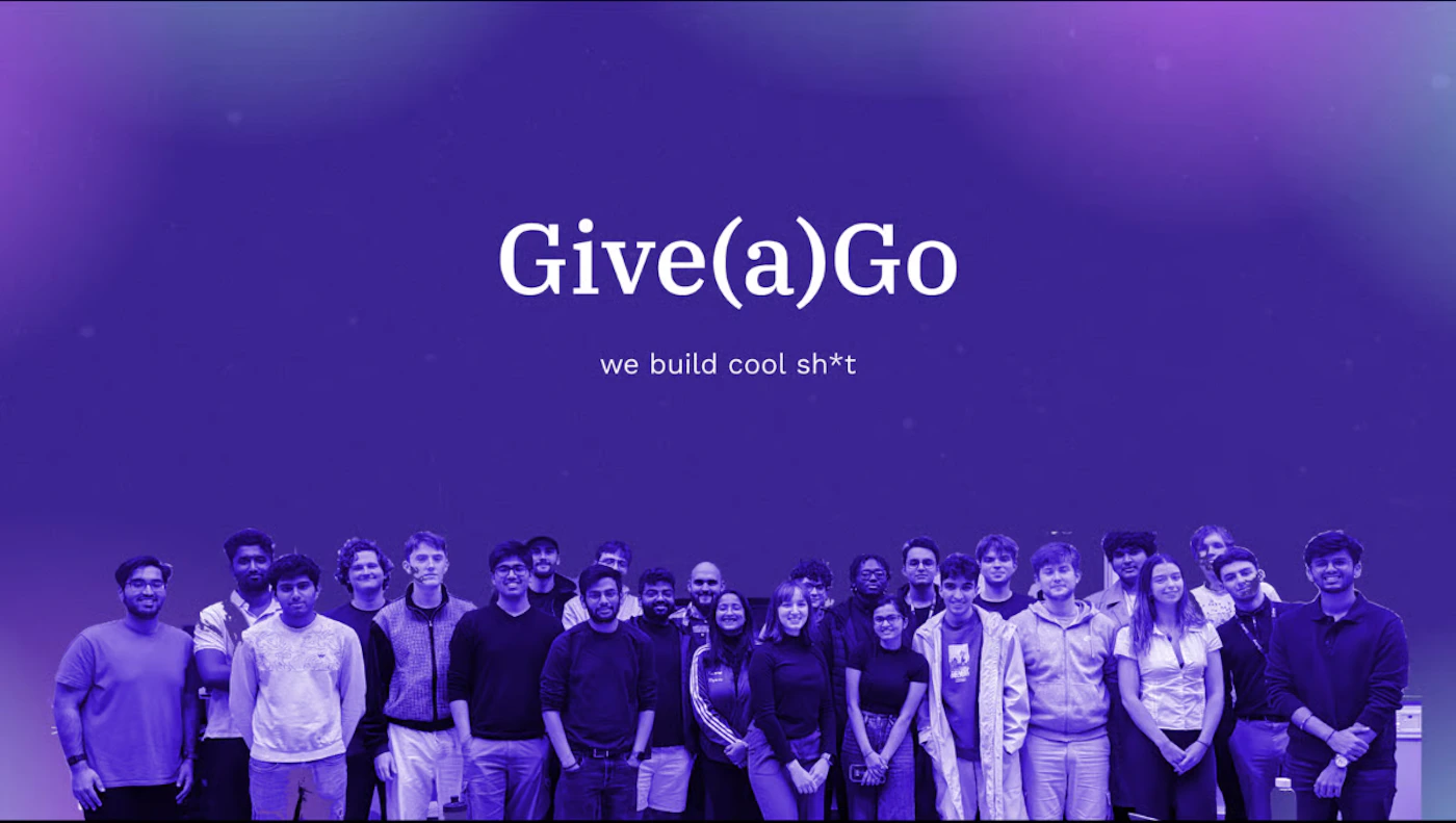 (Banner) A group of approximately twenty-five people stands in a row beneath the company name 'Give(a)Go' and its tagline, all set against a dark purple, gradient background. Text: Give(a)Go we build cool sh*t Modern, bold typography with a dark, vibrant purple color palette. | Colors: #4B0082, #FFFFFF, #300060 Note: This image functions as a promotional or introductory slide/banner, combining large, central text (a name and tagline) with a photo of a team or group set against a stylized background.