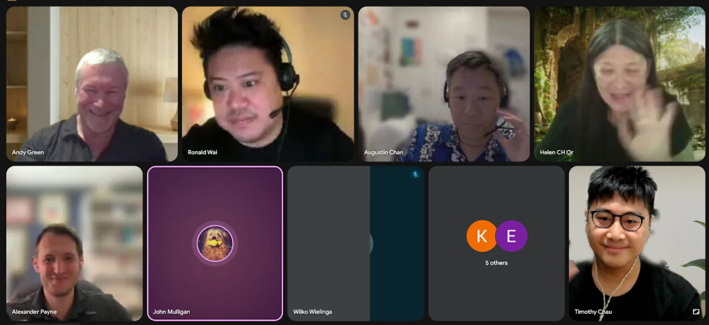 (Photo) A screenshot of a video conference call displaying multiple participants in a grid layout. Some individuals are visible in their video feeds, while others are represented by name labels or initial placeholders. Text: Andy Green Ronald Wai Augustin Chan Helen CH Qr Alexander Payne John Mulligan Wilko Wielinga K E 5 others Timothy Chau people, video conference | virtual meeting, indoor settings for most participants | grid layout of video feeds, some participants wearing headsets, one participant using a virtual background, some cells showing only names or initials | screenshot, candid | Colors: #E8EAED, #202124, #521A52, #F97900, #4A6D3A Note: This image is a digital capture of a screen displaying a live video conference, which is essentially a photograph of a digital interface showing real people and their names. It captures a moment in time from a virtual meeting.