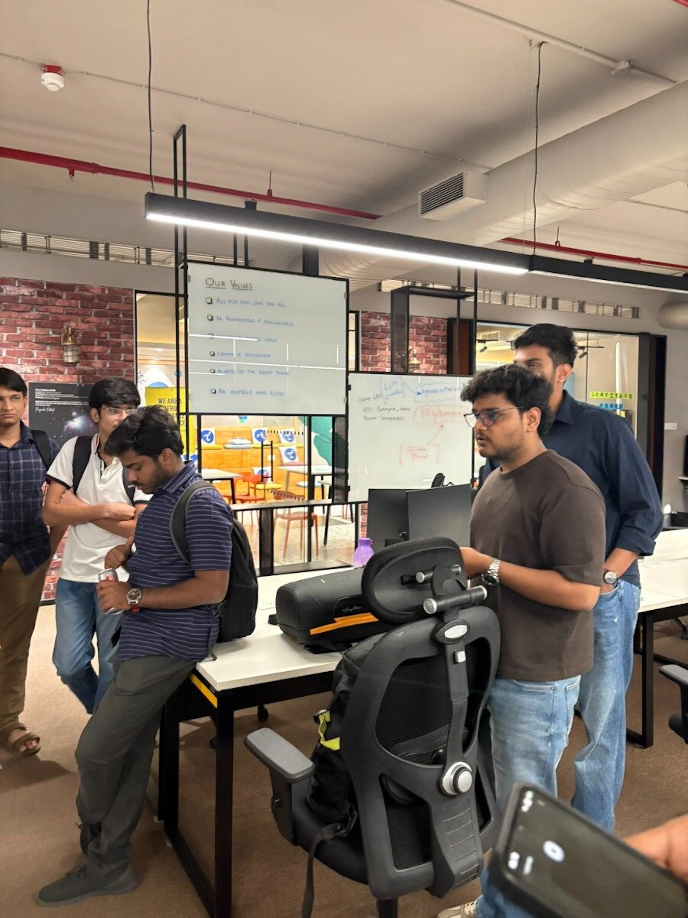 (Photo) A group of young men are gathered in a modern office space, standing around a desk and a whiteboard that lists company values. Text: Our Values ALL FOR ONE, ONE FOR ALL BE RESPONSIBLE & ACCOUNTABLE BE OPEN CREATE A DIFFERENCE ALWAYS DO THE RIGHT THING BE HUMBLE AND KIND LLM Gemma 2 (7B) HF: Transformers Keras Bly/Google GRATITUDE WE ARE... group of people in an office | indoor office workspace | whiteboard with handwritten values, exposed brick wall, office furniture, group discussion | candid | Colors: #FFFFFF, #2C2C2C, #4A6984, #8B4513, #A52A2A Note: This is a real-life photograph capturing a candid moment of people in an indoor office environment.