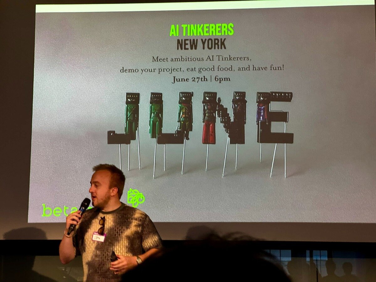 (Banner) The image shows a person speaking into a microphone in front of a large projector screen. The screen displays a presentation slide for an event, featuring text details and a prominent graphic spelling 'JUNE' using letter-shaped objects topped by small, distinct figures. Text: AI TINKERERS NEW YORK Meet ambitious AI Tinkerers, demo your project, eat good food, and have fun! June 27th | 6pm JUNE betat AI Modern and clean typography for the main text, contrasted with a unique, illustrative 3D-like graphic for the word 'JUNE'. | Colors: #D0D0D0, #66FF00, #333333, #000000 Note: The image displays a presentation slide that functions as a promotional graphic for an event, containing key information, a headline, and a distinct visual element, which aligns with the characteristics of a banner.