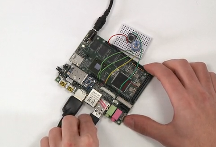 The image shows a circuit board with various components, including a USB port being connected by a hand.