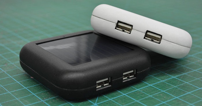 The image shows two small, rectangular devices, one black and one white, with solar panels and USB ports.