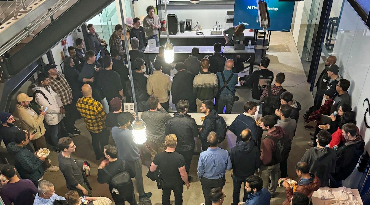 (Photo) A photo of a large group of people gathered in a modern indoor space, possibly at a social or networking event. Text: AI Tinkering Meetup people | indoor | large group, social gathering, presentation or talk | candid Note: The image is a real-life captured scene of people in an indoor environment, making it a photograph.  It depicts a specific event.