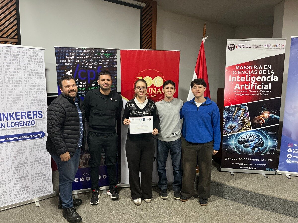 (Photo) A group of five people poses for a photo in front of several banners at an event related to Artificial Intelligence, with one person holding a certificate. Text: AI TINKERERS SAN LORENZO san-lorenzo.aitinkerers.org/ cpf 100 UNA 1926-2026 MAESTRIA EN CIENCIAS DE LA Inteligencia Artificial Innovación, Datos y Sistemas Inteligentes para el Futuro FACULTAD DE INGENIERIA - UNA UNIVERSIDAD NACIONAL DE ASUNCION www.ing.una.py GOBIERNO DEL PARAGUAY PROCIENCIA group of people | indoor event space | people holding a certificate, promotional banners in the background | candid portrait | Colors: #FFFFFF, #000000, #E30613, #004A99 Note: The image is a standard photograph capturing a group of individuals at an indoor event.