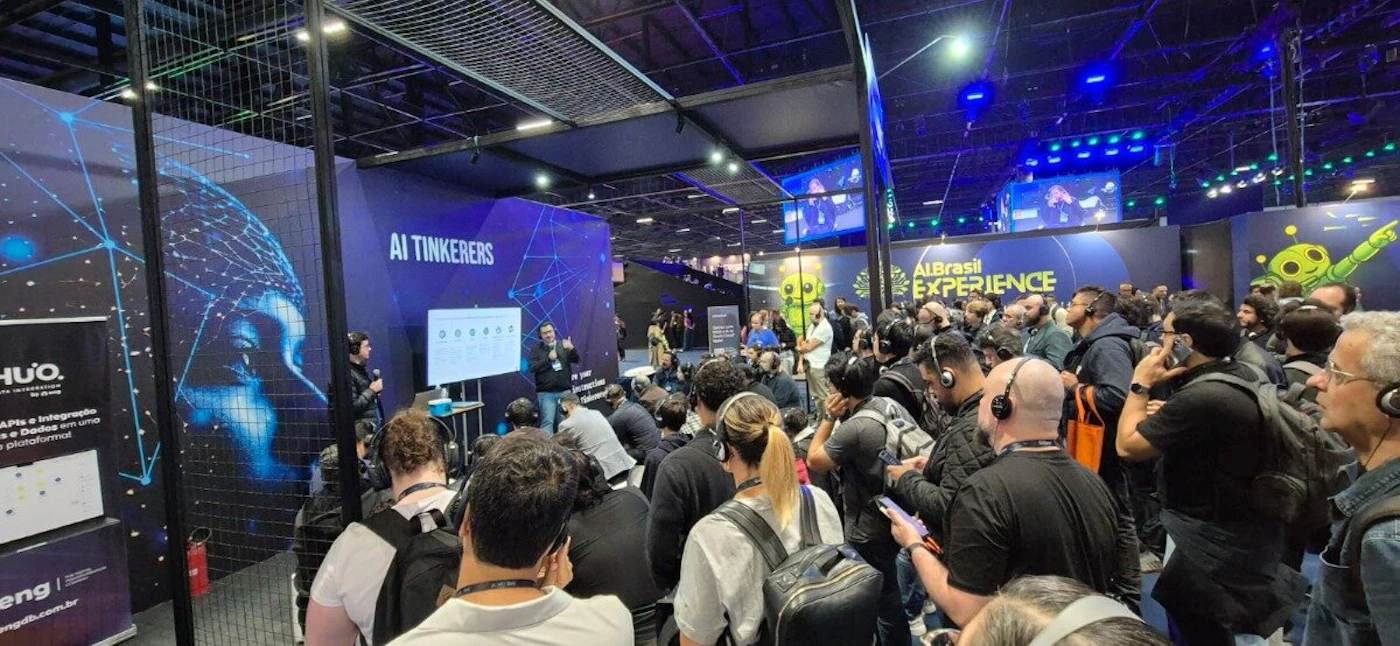 (Photo) A photograph capturing a busy indoor technology conference or exhibition, showing a large crowd gathered around several booths where presentations are taking place under dark blue lighting. Text: HUO. APIs e Integração de Dados em uma plataforma! eng engdb.com.br AI TINKERERS AIBrasil EXPERIENCE People (large crowd), conference booths, technology event | Indoor, large exhibition hall/convention center | Many attendees wearing headphones/headsets; visible branding and presentations related to AI/data; high-tech lighting setup. | Candid, wide-angle shot of a crowd | Colors: #000000, #000033, #2222FF, #FFFFFF Note: The image is a candid capture of a real-world event, documenting a large group of attendees and speakers at an indoor conference or exhibition.