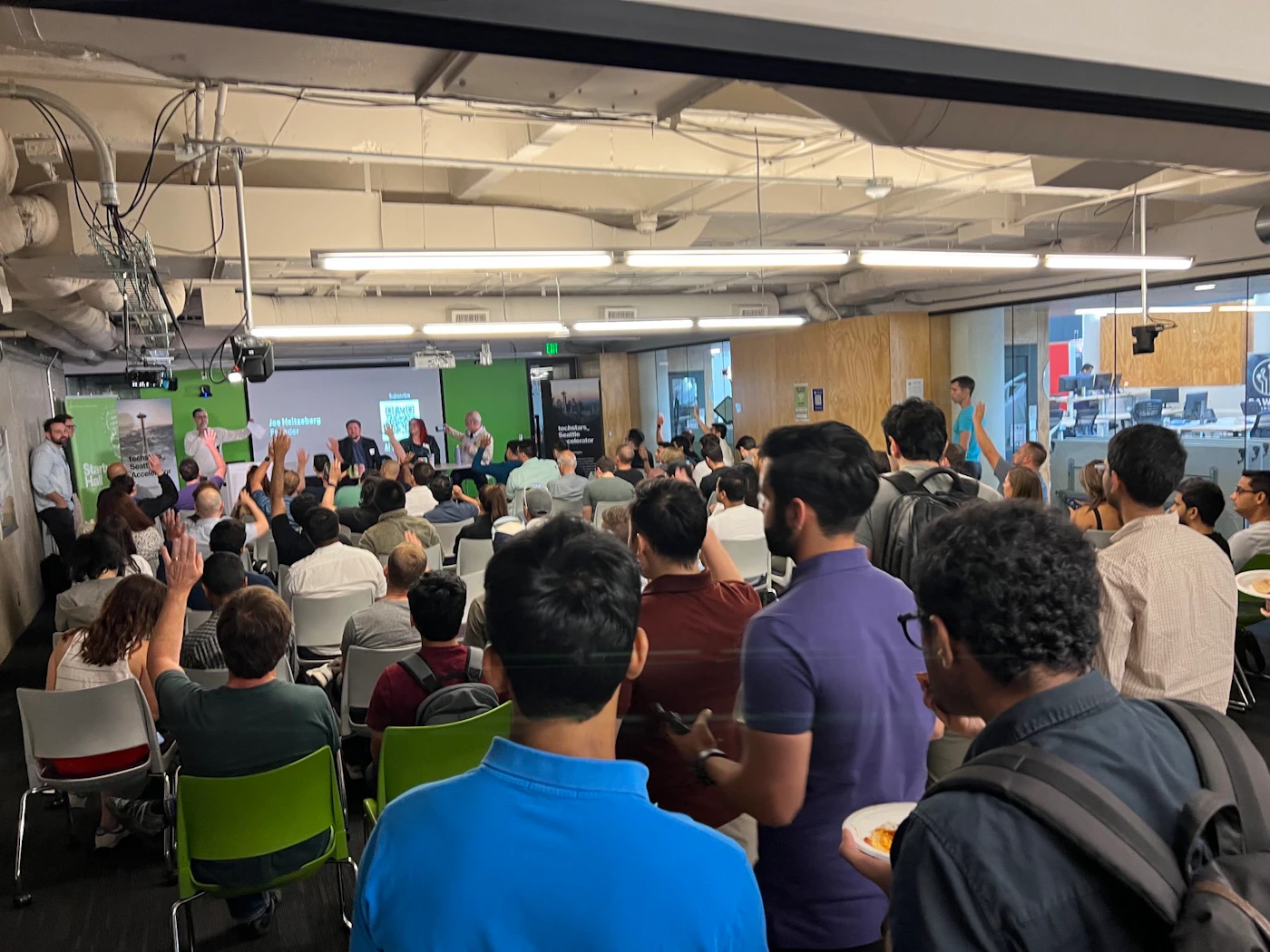 (Photo) A photo of a large group of people in an indoor setting, seemingly attending a presentation or Q&A session. people | indoor | large group, presentation/Q&A setting | candid Note: The image is a real-life captured image of a scene with people, making it a photograph. It doesn't contain any prominent text or design elements that would categorize it as a banner, logo, or illustration.