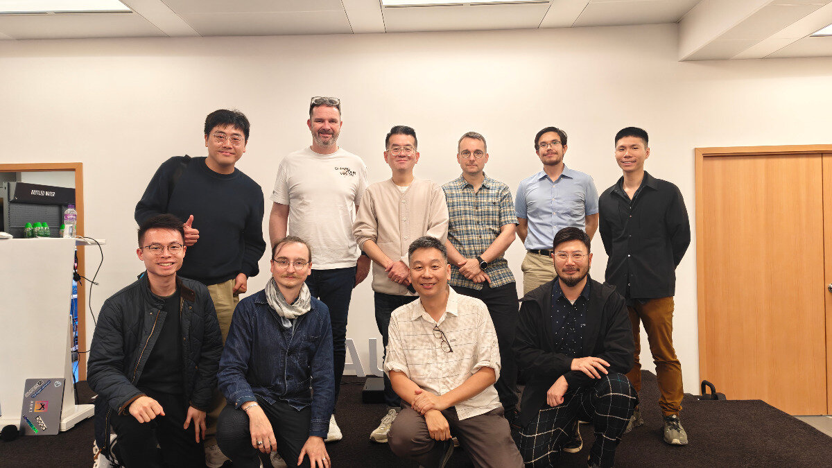 A group of ten men, appearing to be professionals or colleagues, pose for a formal group portrait indoors against a plain white wall.. Text: BOTTLED WATER AL
