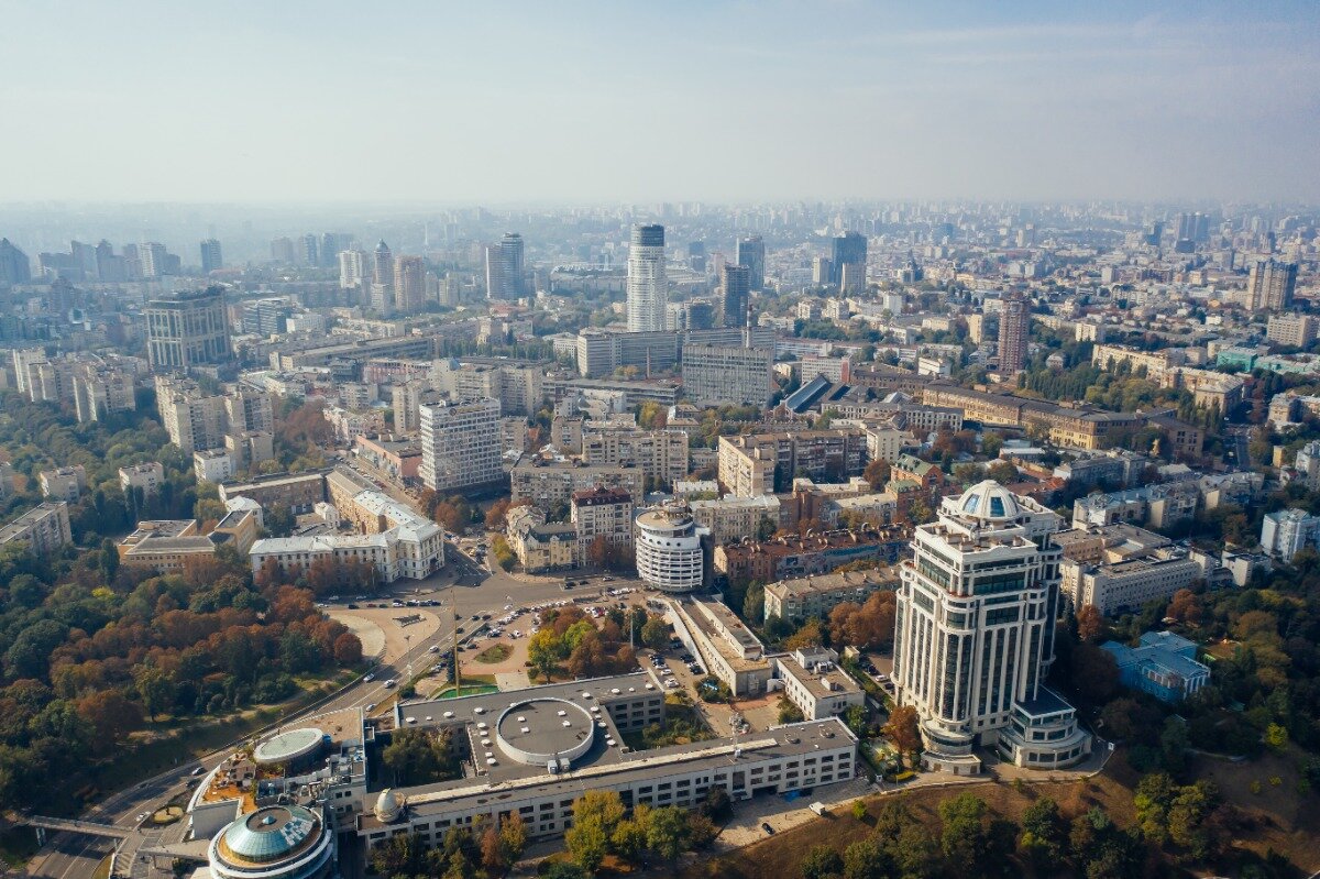 An aerial view of a cityscape with various buildings, roads, and green spaces.
