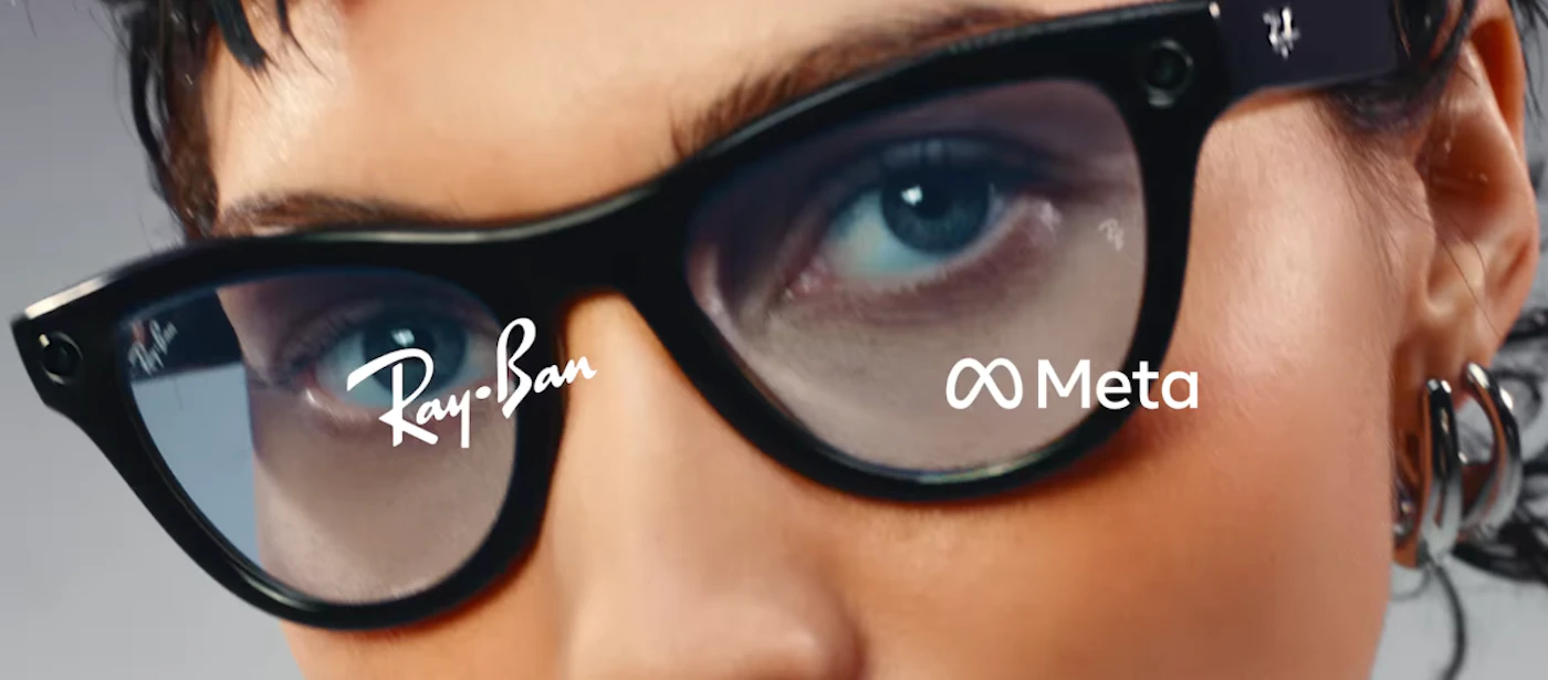 (Photo) A close-up photo of a person wearing Ray-Ban smart glasses, with the Ray-Ban and Meta logos visible. Text: Ray-Ban Meta person | indoor | glasses, logos | close-up Note: The image is a photograph of a person wearing glasses. It captures a real-life scene and is not a drawing, logo, or banner.