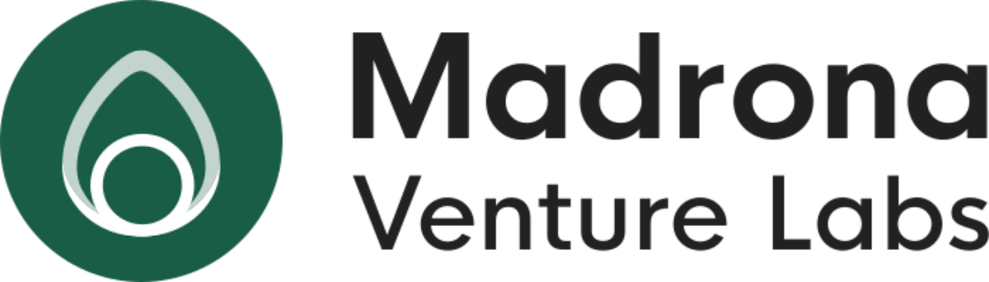 (Logo) A logo for 'Madrona Venture Labs' featuring a light grey abstract flame-like or teardrop shape within a dark green circular emblem, positioned to the left of the company name. Text: Madrona Venture Labs Colors: #235749, #333333, #e0e0e0 Note: The image clearly serves as a brand identifier, combining a distinct graphic symbol with a company name, which is the primary function of a logo.