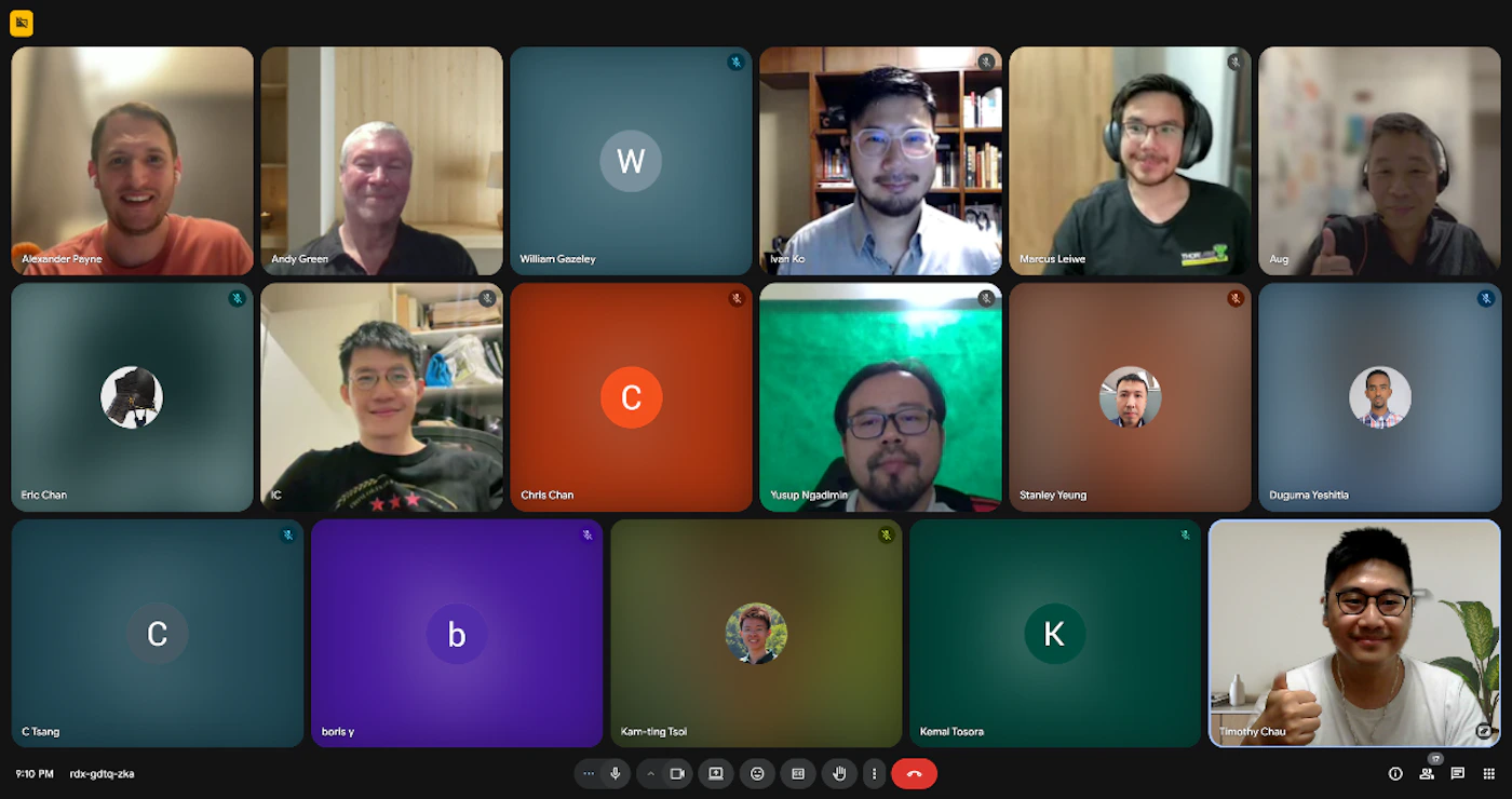 (Photo) A screenshot of a video conference call displaying fifteen participants in a grid layout. Some participants are visible via live video feeds, while others are represented by profile pictures or their initials on colored backgrounds. Text: Alexander Payne Andy Green William Gounley Ivan Ko Marcus Leiwe Aug Eric Chan Chris Chan Yusup Ngadenin Stanley Yeung Duguma Yoshita C Tsung boris y Kam-ting Tsoi Kemal Tosora Timothy Chau W C C b K 9:10 PM rdr-gdtq-zka People participating in a video conference | Virtual meeting environment | Grid layout of 15 participants, mix of live video feeds and static avatars/initials, one person giving a thumbs-up, digital interface elements | Screenshot, digital interface | Colors: #202124, #3C4043, #EA4335, #F9AB00, #8AB4F8 Note: The image is a direct capture of a digital screen displaying a live video conference with multiple participants, which is best categorized as a photo of a user interface.