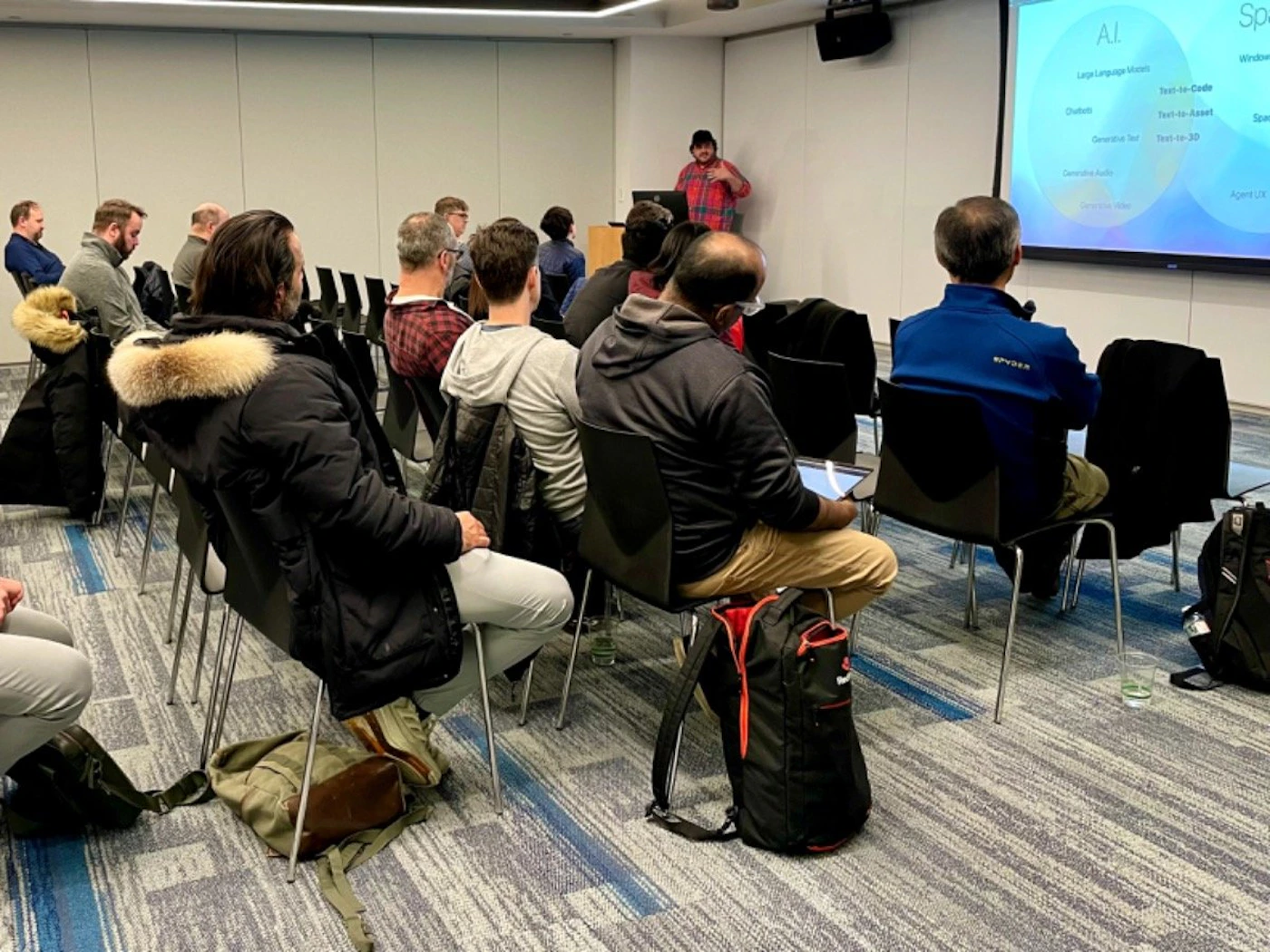 (Photo) A group of people are sitting in chairs in a presentation room, listening to a speaker who is standing and gesturing towards a screen displaying a presentation about AI. Text: AI Large Language Models Text-to-Code Chatbot Text-to-Asset Generation 3D Text-to-2D Demonstration & Audit Sp Windows Sam Agent X NVIDIA people | indoor | presentation, audience, speaker | candid Note: The image is a real-life captured scene of a presentation, depicting people and their environment. This makes it a photograph.