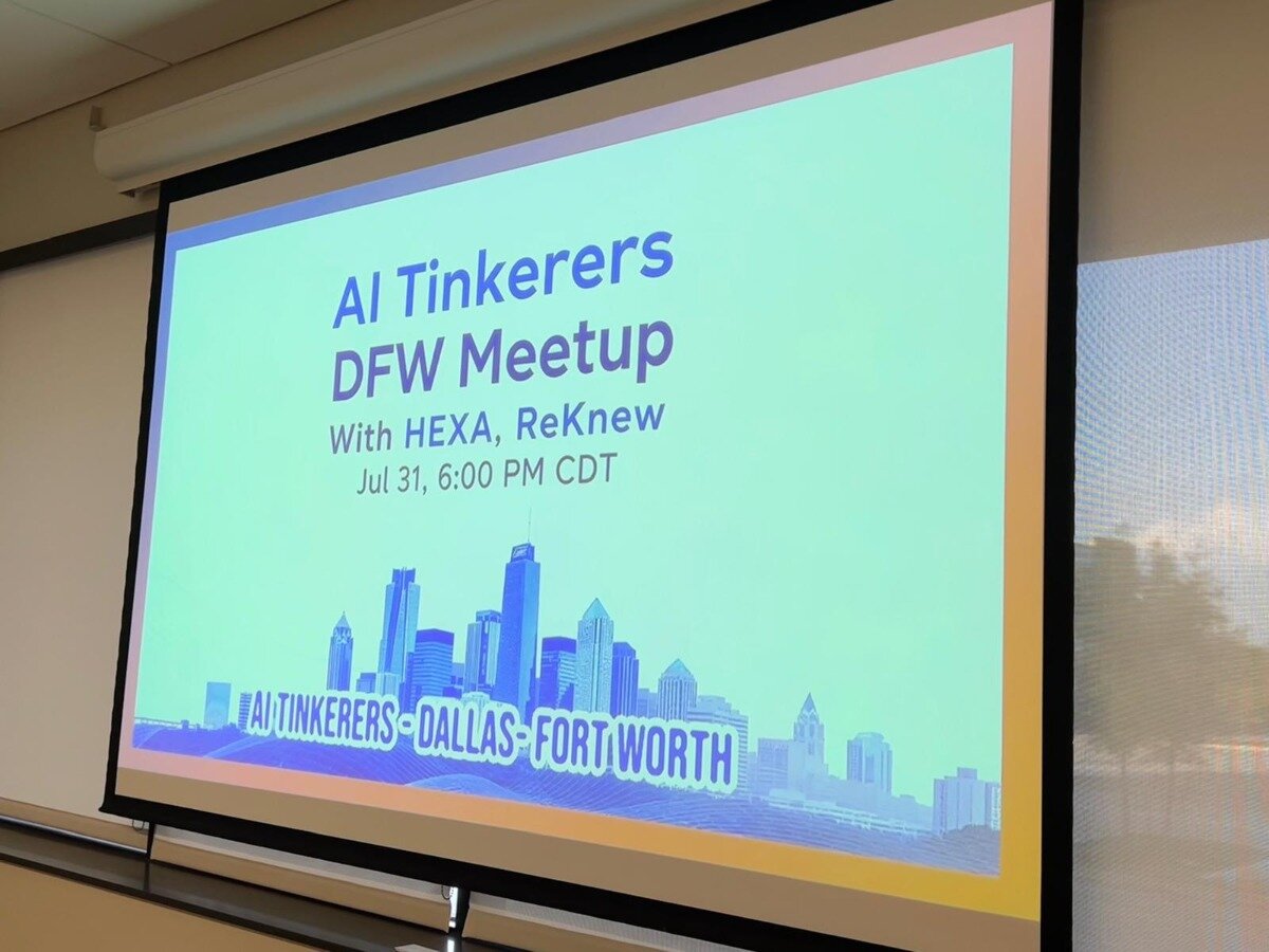 The image displays a projected screen showing a digital banner for an 'AI Tinkerers DFW Meetup'. It features event details, including date and time, against a light green background with a blue and purple city skyline graphic at the bottom.. Text: AI Tinkerers DFW Meetup
With HEXA, ReKnew
Jul 31, 6:00 PM CDT
AI TINKERERS DALLAS - FORT WORTH