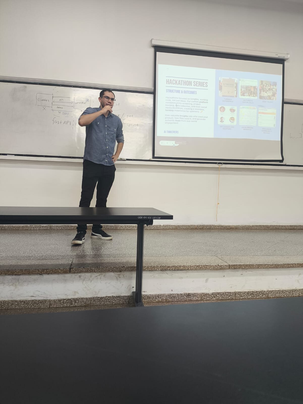 (Photo) A man stands at the front of a room, giving a presentation with a whiteboard and a projection screen behind him. Text: HACKATHON SERIES STRUCTURE & OUTCOMES Hackathons focused on tangible, working code, not just ideas. Our custom platform combines entry screening, project tracking, data collection, and even social media activation, creating a seamless, turnkey experience for sponsors. Gain valuable insights into who uses your product, how they used it, and generate authentic buzz from real-world engagement. AI TINKERERS Clients API fast API POST / pat endpoint person | indoor | presentation, whiteboard, projection screen | candid | Colors: #f2f2f2, #607b9b, #1a1a1a, #d9e8ef Note: The image is a real-life photograph capturing a person in an indoor environment during a presentation.