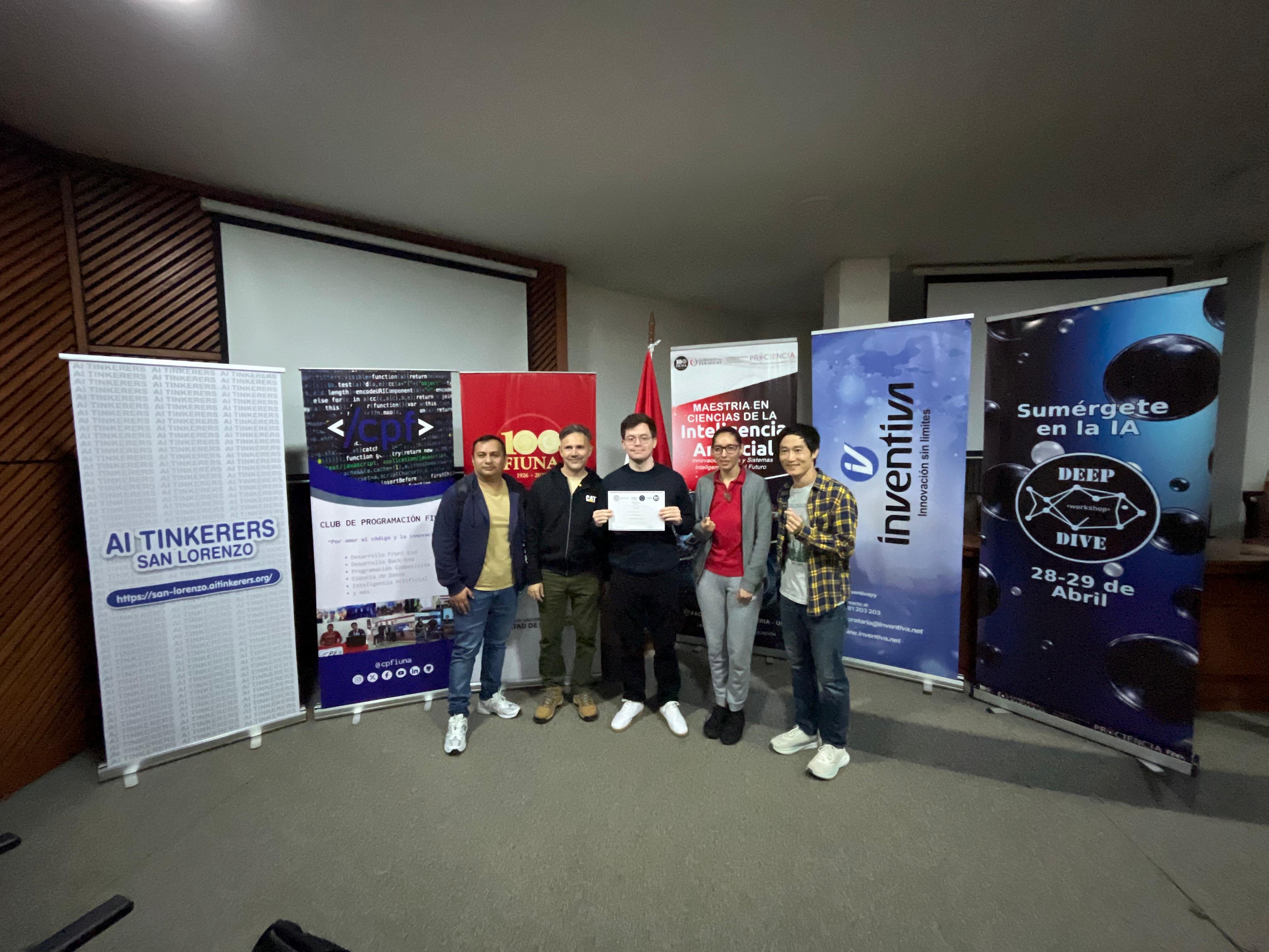 (Photo) A group of five people stands in a line in front of several informational banners at an indoor event, with one person holding a certificate. Text: AI TINKERERS SAN LORENZO https://san-lorenzo.aitinkerers.org/ </cpf> CLUB DE PROGRAMACIÓN FIUNA @cpfiuna 100 FIUNA 1926 - 2026 MAESTRÍA EN CIENCIAS DE LA Inteligencia Artificial Informática y Sistemas Inteligentes para el Futuro inventiva innovación sin límites Sumérgete en la IA DEEP DIVE 28-29 de Abril group of people | indoor auditorium or classroom | promotional roll-up banners, certificate, university setting | group portrait | Colors: #ffffff, #004a99, #e31e24, #000000 Note: This is a real-life photograph capturing a group of individuals at what appears to be an academic or professional event.